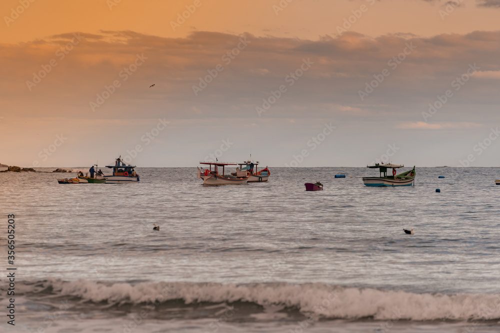 fishing boats in the sea at dusk, slightly choppy sea with colorful clouds