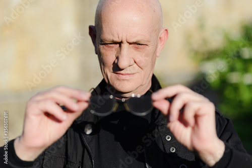 Old man holds vision glasses in his hand. High quality photo