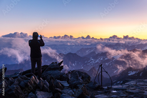 Silhouette of an photographer in the Alps photographing the sunset. View from the way to Grossglockner rock summit, Kals am Grossglockner, Austria