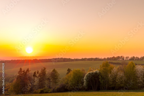 The setting sun over the forested mountain landscape of the Beskydy region, the sun sets beyond the horizon. © Lukas