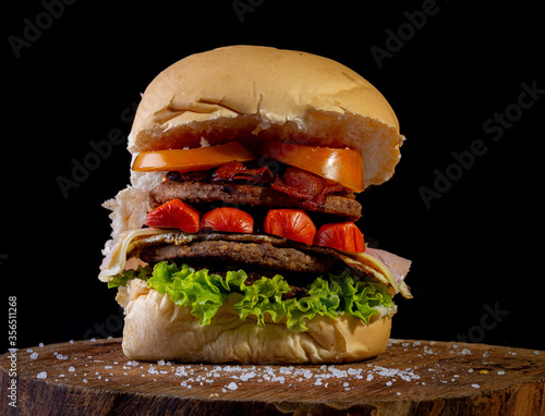 Big homemade burger with two beef burger, lettuce, tomato, sausage, ham, bacon and cheese, AKA X-tudo in Brazil.. photo