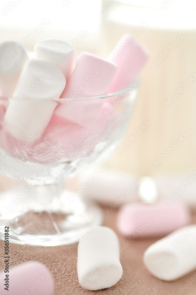 marshmallows in a glass bowl stands on a light table with a milk. marshmallows in a glass bowl stands on a light table with a milk.