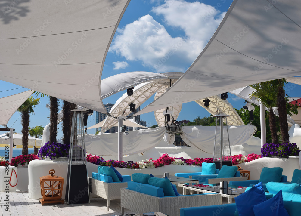 Empty summer beach cafe with white parasols and blue sofas