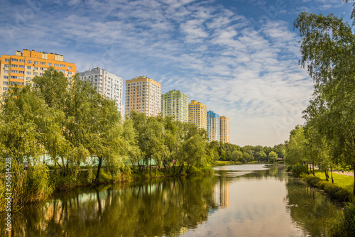 Landscape from sity park  Kyiv. Ukraine. Little river  hot summer  bright green trees and high buildings