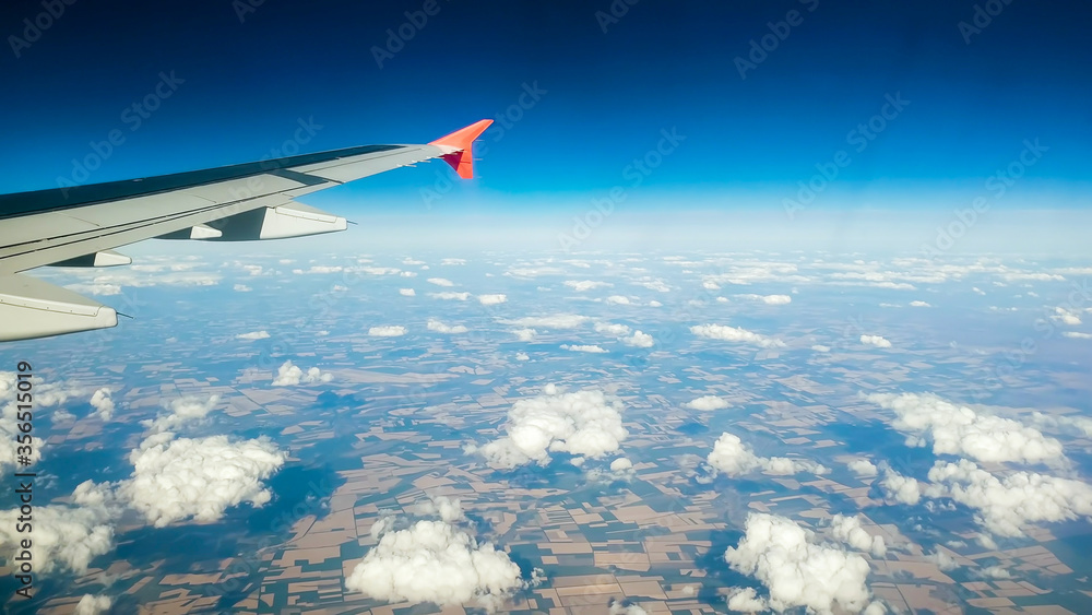 Fototapeta premium Toned image of airplane wing flying above clouds and land