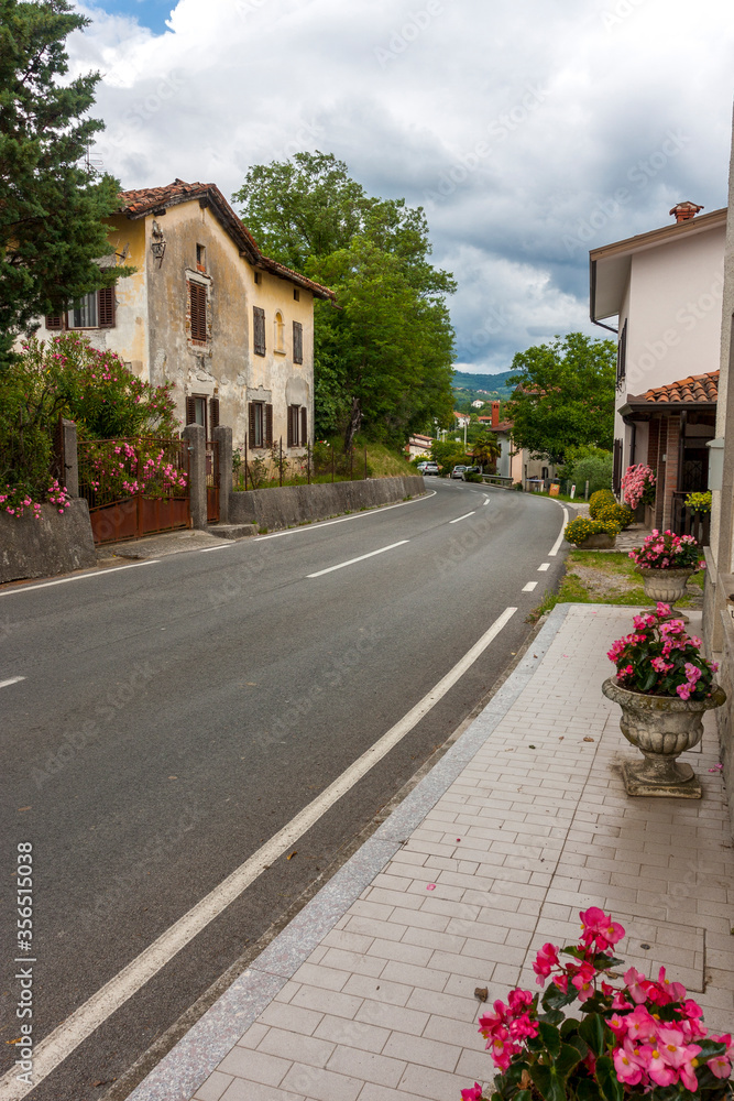 The street of the old small town drowning in greenery against a blue sky with clouds