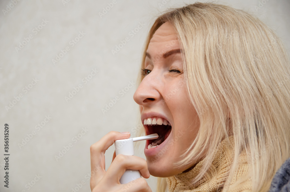 blonde girl with a scarf around her neck and a grimace of disgust pours throat spray, copying the space. Concept of medicine, health. blonde girl with a scarf around her neck and a grimace of disgust pours throat spray, copying the space. Concept of medicine, health.