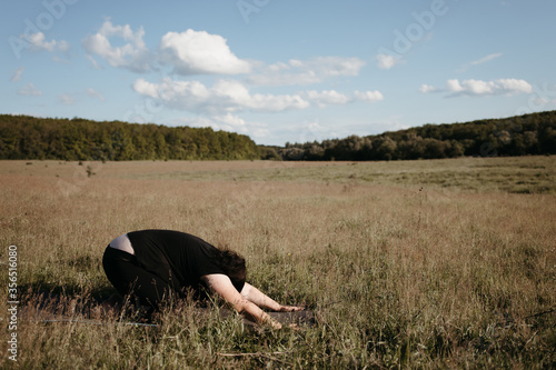 Young overweight woman doing yoga exercises in nature. Healthy lifestyle, sport, weight loss, activity concept © Vadym