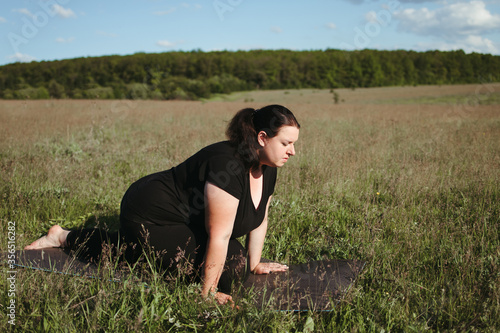 Young overweight woman doing yoga exercises in nature. Healthy lifestyle, sport, weight loss, activity concept © Vadym