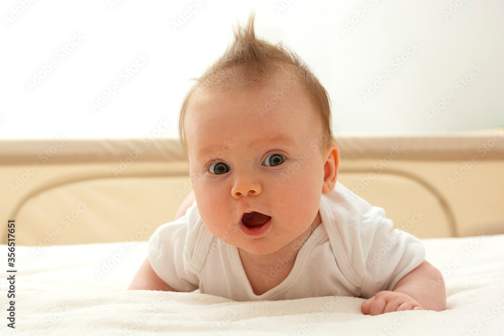 Cute happy newborn baby learning to sit on her tummy. Smiling baby with blue eyes. Cute happy newborn baby learning to sit on her tummy. Smiling baby with blue eyes.