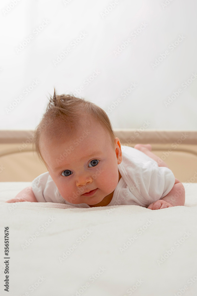 Newborn baby girl sitting on her tummy. Smiling baby with blue eyes.