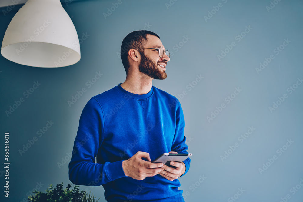 Naklejka premium Cheerful young bearded caucasian hipster guy enjoying modern digital tablet for work and education
