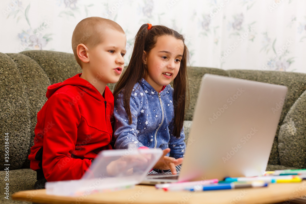 Distance learning online education. school boy and girl studying at home with laptop notebook and doing homework. Sitting at a table Distance learning online education. school boy and girl studying at home with laptop notebook and doing homework. Sitting at a table