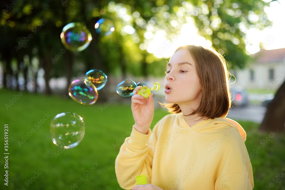 Pretty teenage girl blowing soap bubbles on a sunset. Child having fun in a park in summer. Pretty teenage girl blowing soap bubbles on a sunset. Child having fun in a park in summer.