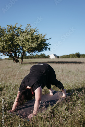 Overweight woman doing yoga exercises outdoors. Healthy lifestyle, open air workout, weight loss © Vadym