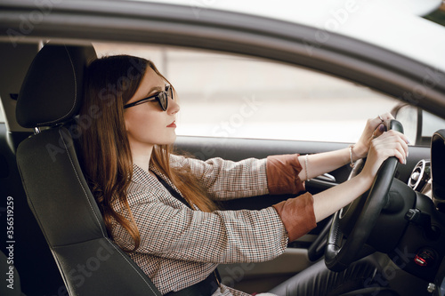 Beautiful young girl sitting behind the wheel of a luxury car