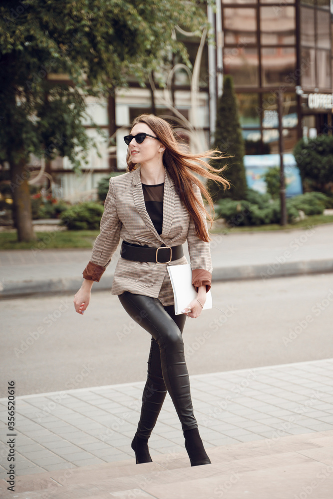 Fototapeta premium Beautiful young girl in a business suit on a background of business center. Business theme