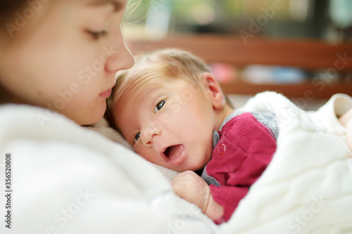 Cute big sister admiring her newborn brother. Adorable teenage girl holding her new baby boy brother. Kids with large age gap. Big age difference between siblings.