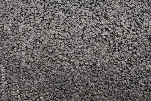 gray black granular asphalt road with small stones. rough surface texture