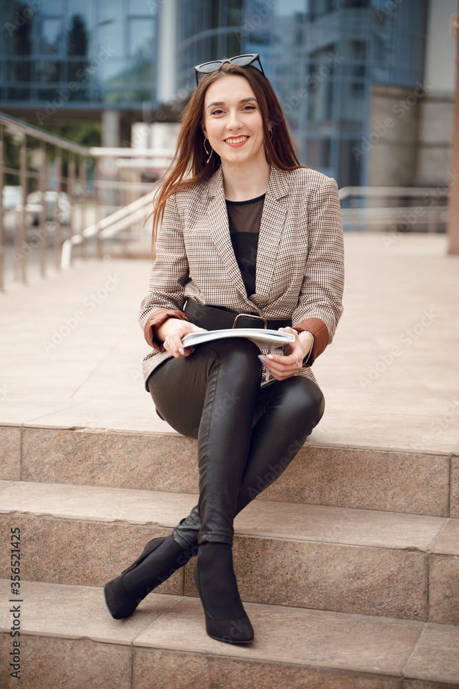 Beautiful young girl in a business suit on a background of business center. Business theme Beautiful young girl in a business suit on a background of business center. Business theme
