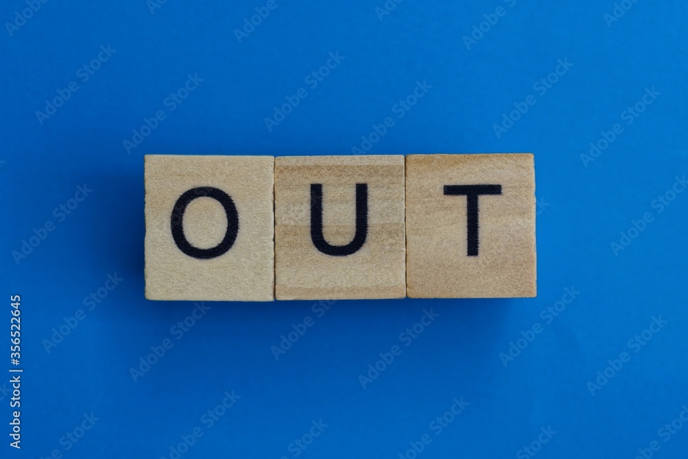 text on gray word out in small wooden letters with black font on a blue background text on gray word out in small wooden letters with black font on a blue background