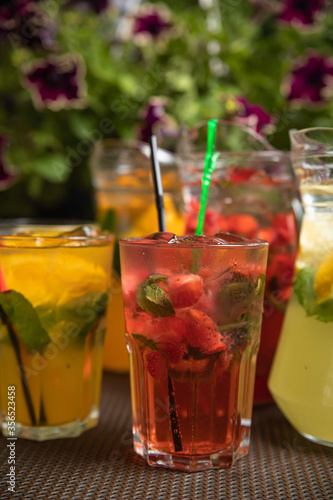 Homemade strawberry ice tea in the garden. Strawberries, mint and lemon balm leaves, ice and green tea.