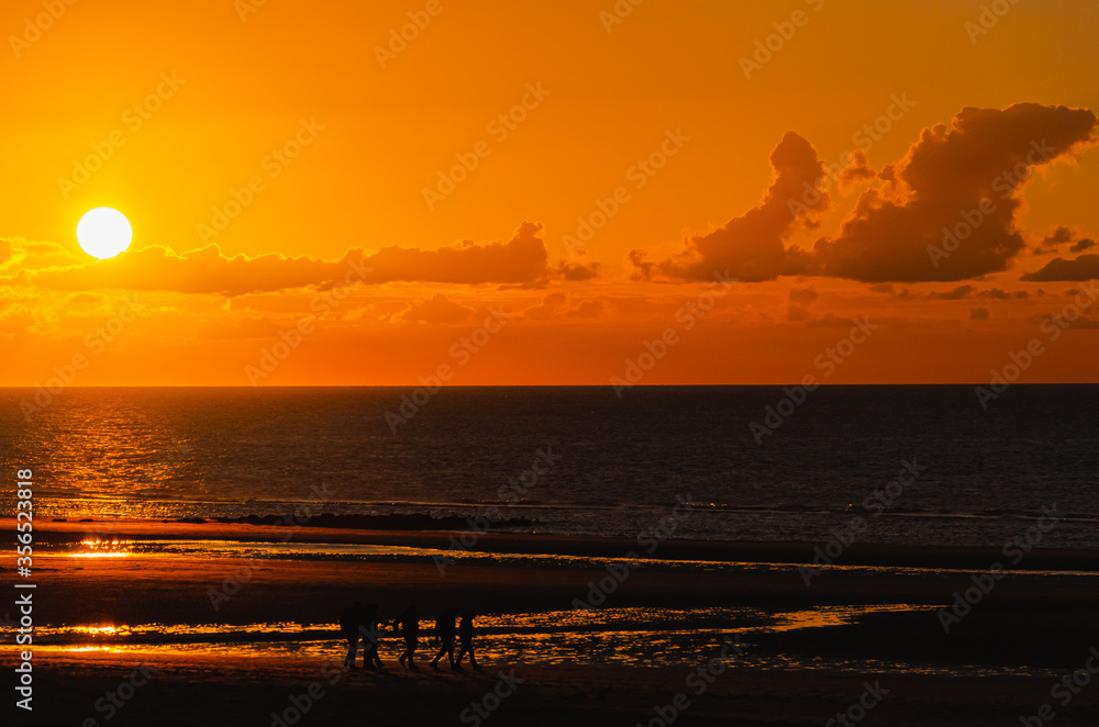 Beautiful sunset above the ocean with silhouettes Ostend (Oostende) city beach at sunset by the North Sea, Belgium.