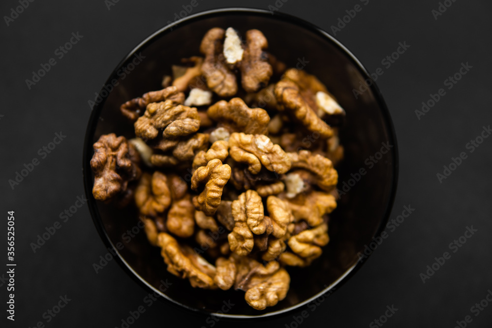Walnut in a small plate on a black table. Walnuts is a healthy vegetarian protein nutritious food. Natural nuts snacks. Walnut in a small plate on a black table. Walnuts is a healthy vegetarian protein nutritious food. Natural nuts snacks.