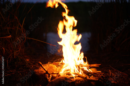 Bonfire at lake campsite at dusk 