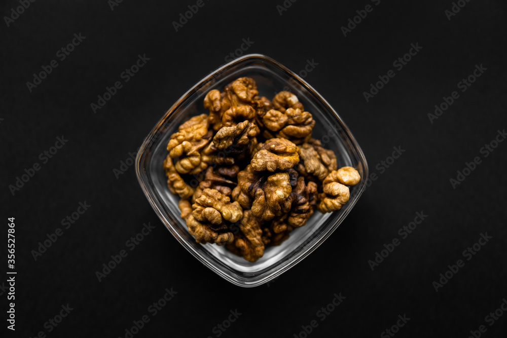 Walnut in a small plate on a black table. Walnuts is a healthy vegetarian protein nutritious food. Natural nuts snacks. Walnut in a small plate on a black table. Walnuts is a healthy vegetarian protein nutritious food. Natural nuts snacks.