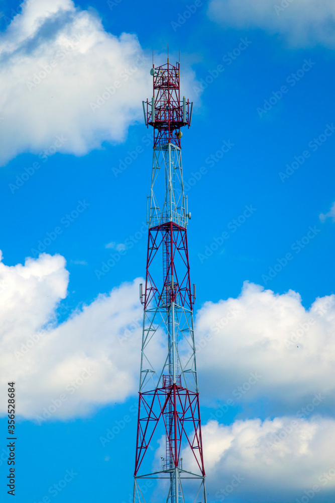 a mobile phone tower against a background of blue sky and white clouds.sunny day.communication technology