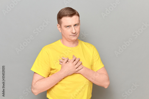 Portrait of man holding hands on chest and thanking somebody