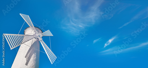 Fototapeta Naklejka Na Ścianę i Meble -  Old lighthouse in Swinoujscie, a port in Poland on the Baltic Sea. The lighthouse was designed as a traditional windmill. Panoramic image, banner design with copy-space, place for text on blue sky.