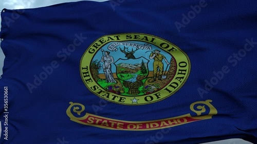 Flag of Idaho waving in the wind against deep beautiful clouds sky photo