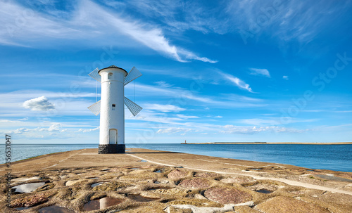 Panoramic image of seawall and old whitewashed windmill lighthouse in Swinoujscie, a port in Poland on the Baltic Sea.