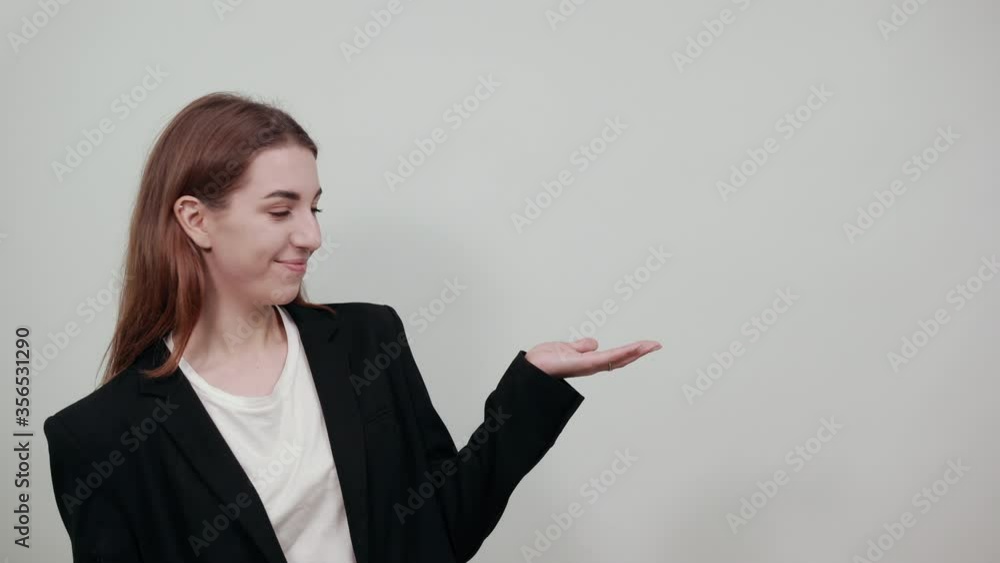 Palms up, place your product here, raising arms wide spread is catching something. Young attractive woman with brown hair in a light t-shirt and black jacket on white background Palms up, place your product here, raising arms wide spread is catching something. Young attractive woman with brown hair in a light t-shirt and black jacket on white background