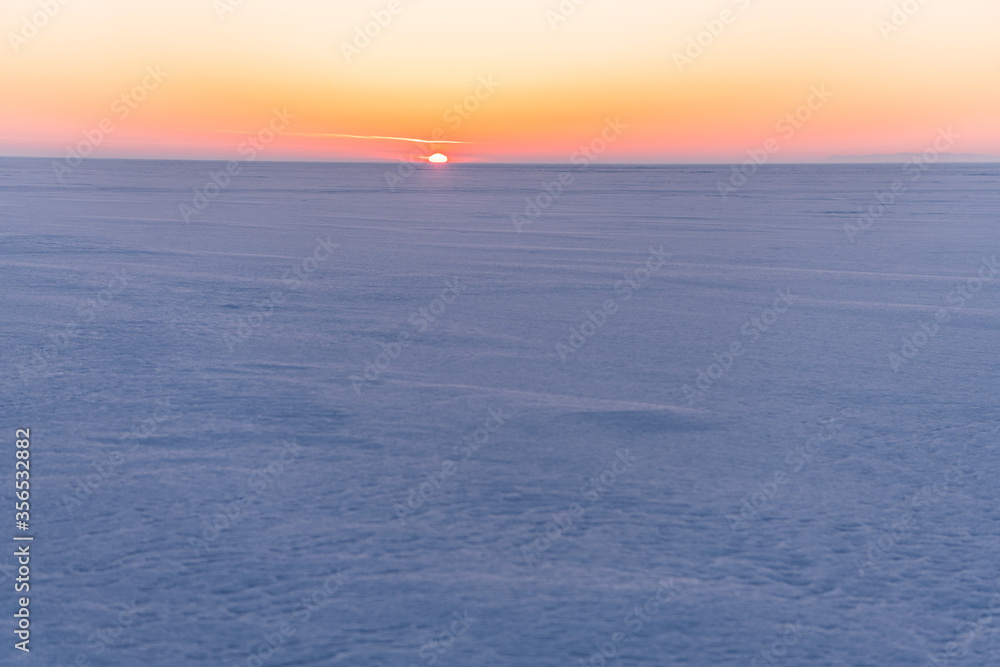 Snow-covered surface of Baikal Lake on the sunset