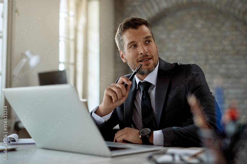 Smiling businessman using laptop while working in the office. Smiling businessman using laptop while working in the office.
