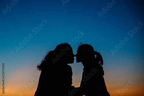 Gay couple kissing with sunset in background.