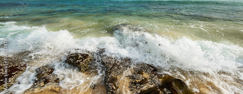 Panorama sea water flowing over rocks on the beach.