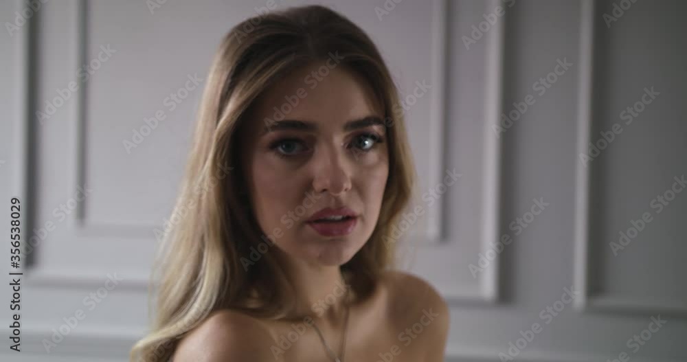 Young woman looks at the camera with a charming look without looking away. Camera movement to the right Young woman looks at the camera with a charming look without looking away. Camera movement to the right