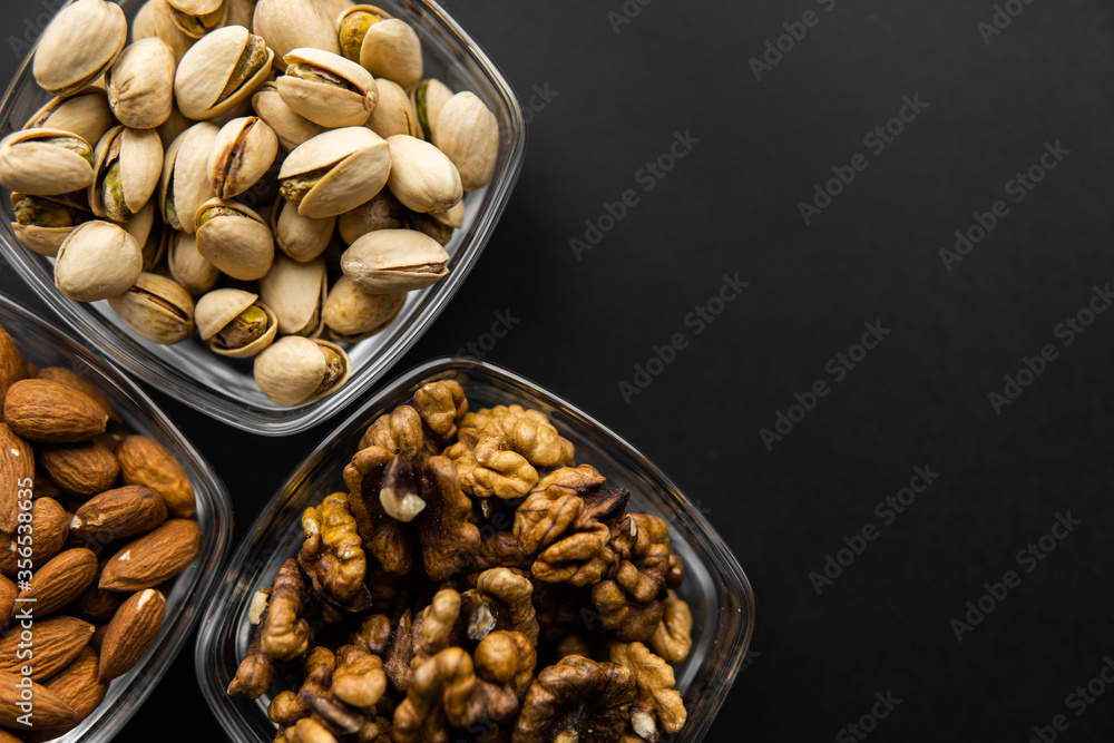 Almond, pistachio and walnut in a small plates which standing on a black table. Nuts is a healthy vegetarian protein and nutritious food. Almond, pistachio and walnut in a small plates which standing on a black table. Nuts is a healthy vegetarian protein and nutritious food.