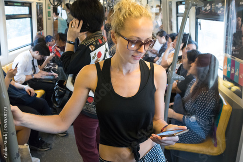 Photography Caucasian female traveler using mobile phone on public transport metro in Kuala Lumpur,capital of Malaysia