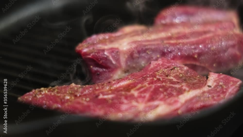 roasting steaks on frying pan at kitchen, closeup