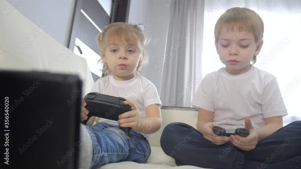 children play console in gamepads teamwork. kids a boy and a girl are playing a portable set-top box in a TV controller. happy family little boy and lifestyle girl have online fun games children play console in gamepads teamwork. kids a boy and a girl are playing a portable set-top box in a TV controller. happy family little boy and lifestyle girl have online fun games