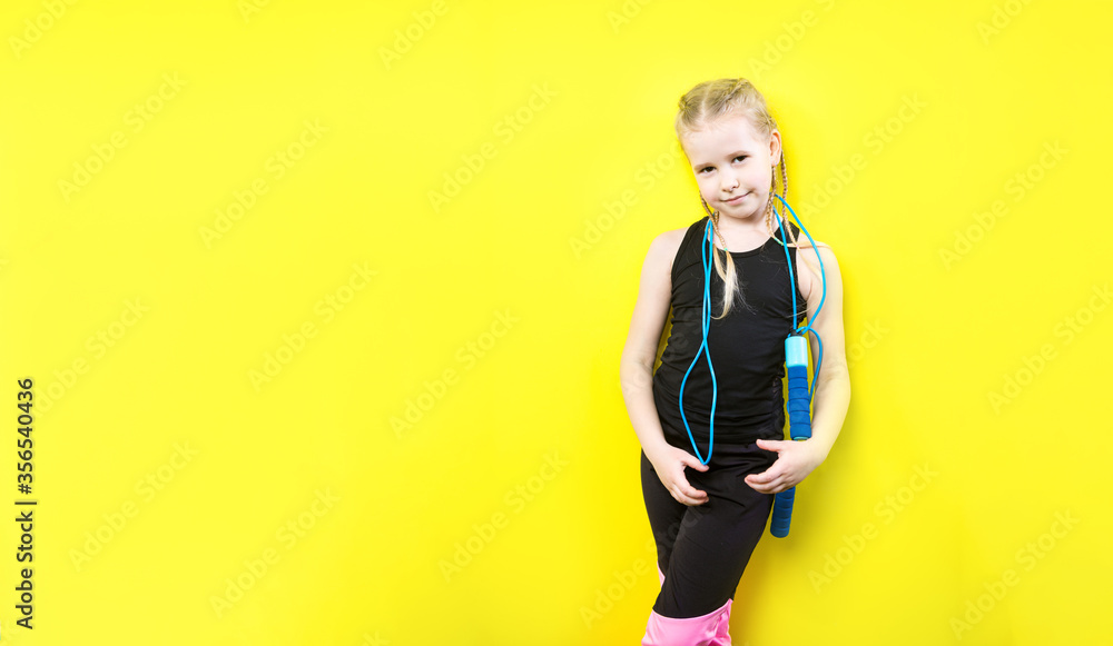 Theme sport and health. Beautiful caucasian child girl with pigtails posing yellow background with smile. little athlete holds sport rope in hands. Banner advertising, space for text copy space blank Theme sport and health. Beautiful caucasian child girl with pigtails posing yellow background with smile. little athlete holds sport rope in hands. Banner advertising, space for text copy space blank