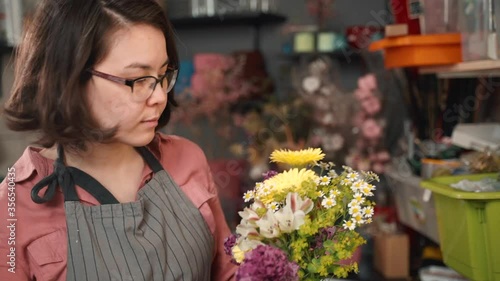 Florist woman make a bouquet of beautiful flowers. Floral art concept. Working girl in store. Professional making wildflowers and selling in shop. Businesswoman small business owner.