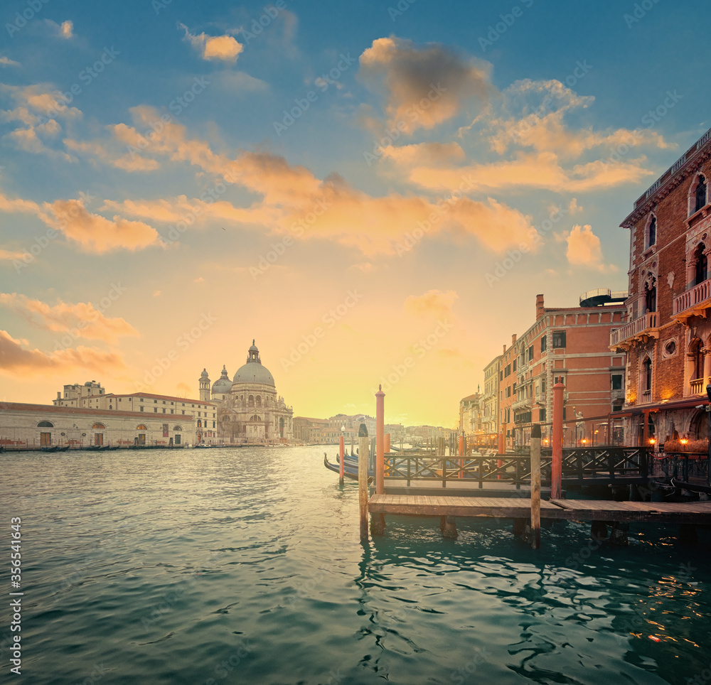 Beautiful golden sunset on Venice's Grand Canal with the Basilica di Santa Maria della Salute and hotels with piers