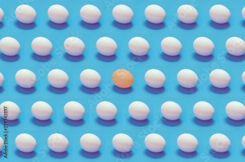 Single colored egg among white eggs solid color background