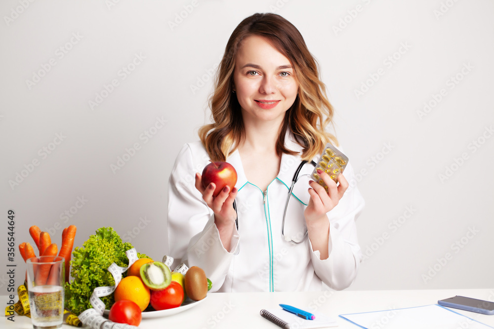 Young dietitian doctor at consulting room at table with fresh vegetables and fruits
